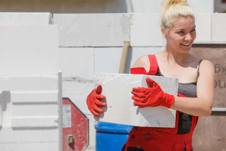 Strong pretty woman working on construction site, building house, installing gray airbricks. Industrial work concept.の写真素材
