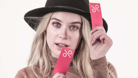 Woman in hat showing tag with shopping sale percentage sign enjoying cheap clothing. Female wearing stylish outfit.の写真素材