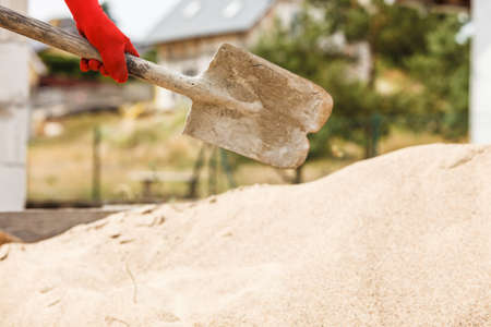 Unrecognizable person worker using shovel standing on industrial construction site, working hard on house renovation.の写真素材