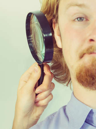 Man having his health or hygiene inspected. Person looking into boy ear using magnifying glass