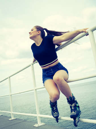 Happy joyful young woman wearing roller skates on sea. Girl having fun during summer time.の写真素材