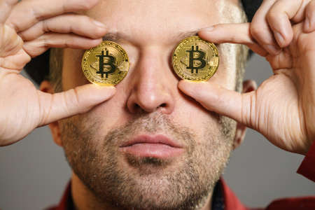 Adult man having bitcoin coin as pince nez in eye. Crypto internet currency banking concept.の写真素材