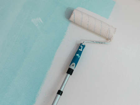 Person appplying paint on wall using roller brush. Home renovation concept.