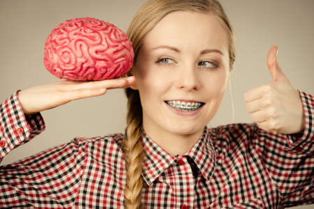 Intellectual expressions, being focused concept. Closeup of attractive woman happy thinking face expression holding brain showing thumbs upの写真素材
