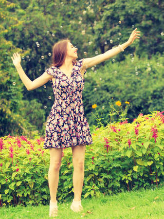 Happiness and carefree concept. Young woman having fun blowing soap bubbles outdoor in parkの写真素材