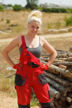 Happy blonde woman wearing dungarees about to do some work on construction site. Women power, gender equality, industrial worker.の写真素材