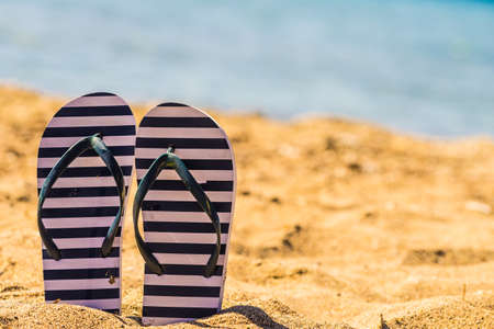Blue and white flip flops on sand beach during summer time weather.の写真素材