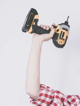 Unrecognizable woman holding yellow driller about to drill something. Hardware construction site objects concept.の写真素材