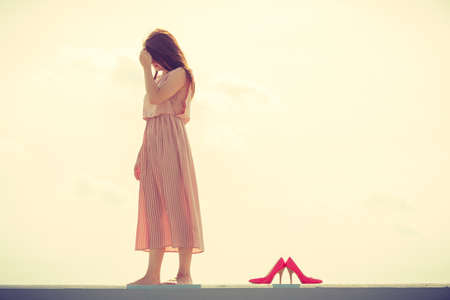 Hobby, idyllic aspects of femininity concept. Woman walking on jetty without shoes wearing beautiful long light pink dress.の写真素材