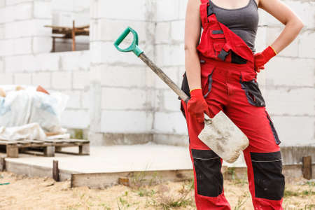Unrecognizable person worker using shovel standing on industrial construction site, working hard on house renovation.の写真素材