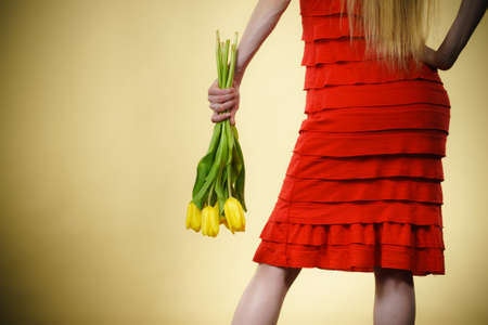 International women day, eight march. woman wearing red dress clothing holding yellow tulips, back view. Mothers day.の写真素材
