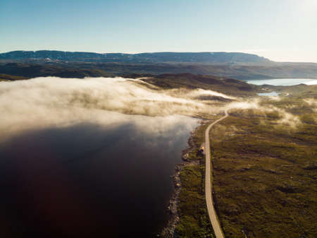 Aerial view. Road crossing Hardangervidda mountain plateau, clouds over lakes, morning time. Norway landscape. National tourist Hardangervidda route.の写真素材