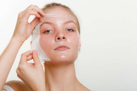 Beauty skin care cosmetics and health concept. Young woman face, girl removing facial peel off mask. Peeling.の写真素材