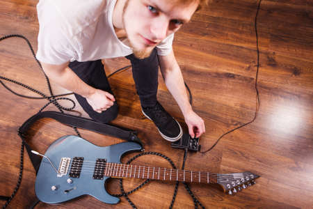 Man with musical instrument setting up guitar audio stomp box effects and cables in music studio