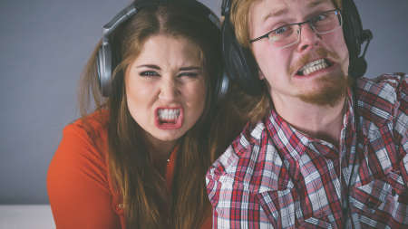Couple enjoying leisure time by playing video games together, man and woman being emotional by game.の写真素材