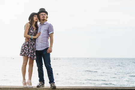 Vintage funny retro couple, man and woman enjoying their romantic date outside wearing fedora hats by seasideの写真素材