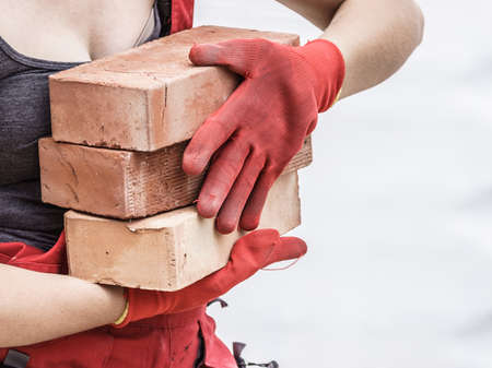 Unrecognizable woman working on construction site, building house, installing bricks. Industrial work concept.の写真素材