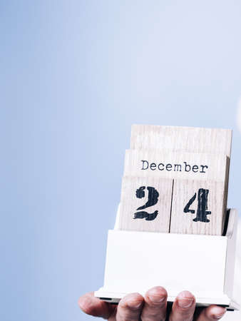 Man holding calendar with 24 december date in hands, on dark blue. Christmas eve time.