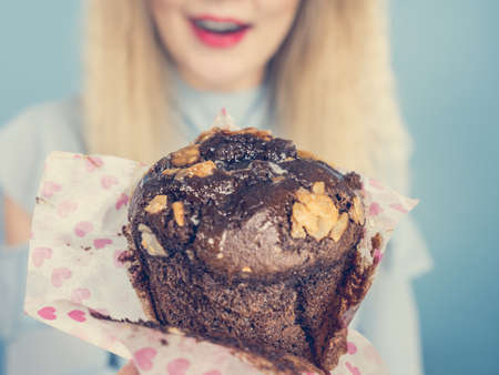 Sweet food sugar make us happy. Attractive blonde woman holds yummy chocolate cupcake in hand, open...