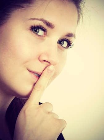 Woman showing silence shh gesture with finger close to mouth asking for being quiet
