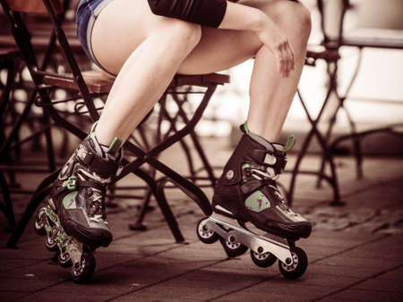 Woman wearing roller skates sitting in town. Female being sporty having fun during summer time.の写真素材
