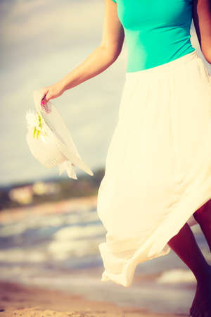 Attractive blonde woman wearing long romantic dress walking on beach and relaxing during summer.の写真素材