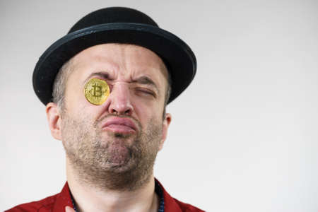 Adult man having bitcoin coin as pince nez in eye. Crypto internet currency banking concept.の写真素材