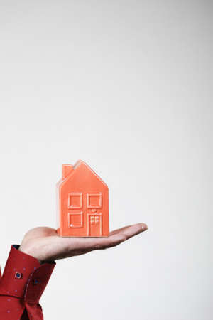 Unrecognizable man holding small red house model on palm of hand. Real estate concept.の写真素材
