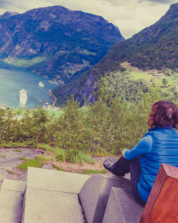 Tourism vacation and travel. Female tourist enjoying beautiful view over magical Geirangerfjorden from Flydalsjuvet viewpoint, Norway. Tourist attraction.の写真素材