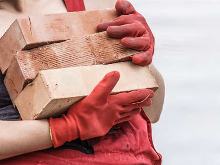 Unrecognizable woman working on construction site, building house, installing bricks. Industrial work concept.の写真素材