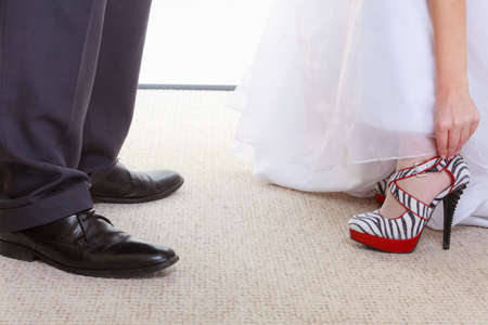 Fashion contrast, clothes, clothing concept. Woman wearing zebra pattern high heels and white wedding dress, man groom standing next to herの写真素材