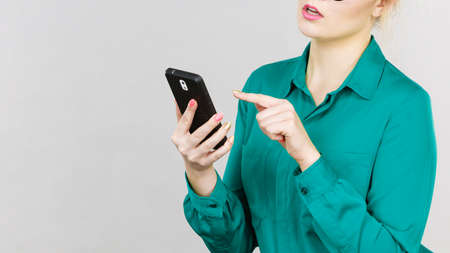 Focused business woman wearing blue shirt looking at phone, checking social media
