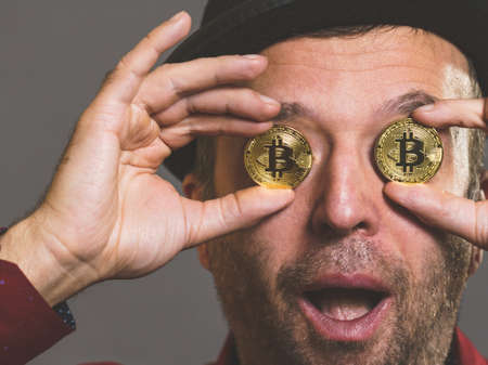 Adult man having bitcoin coin as pince nez in eye. Crypto internet currency banking concept.の写真素材