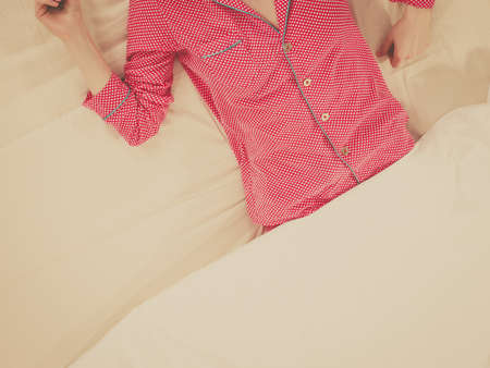 Woman lying on bed wearing cute pink pajamas. Lovely pyjamas sleepwear concept.の写真素材