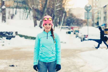 Girl doing urban workout during winter. Lady exercising on snowy streets. Health fitness fashion...