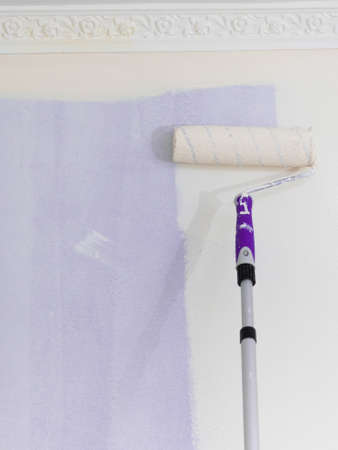 Person appplying paint on wall using roller brush. Home renovation concept.の写真素材