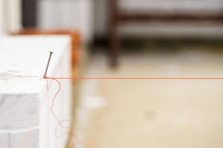 Close up of string net placed on spike nail. Tool to help you set straight distances, spirit level.