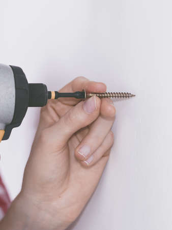 Unrecognizable woman holding driller about to drill something. Hardware construction site objects concept.の写真素材
