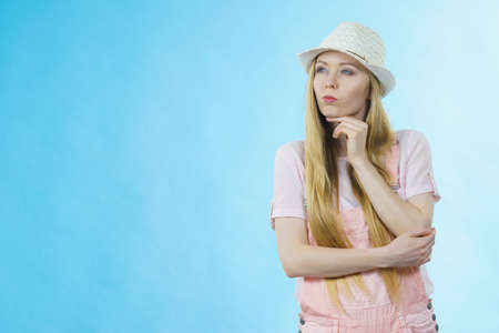 Cute teenage young woman ready for summer wearing pink outfit and sun hat thinking about something.の写真素材