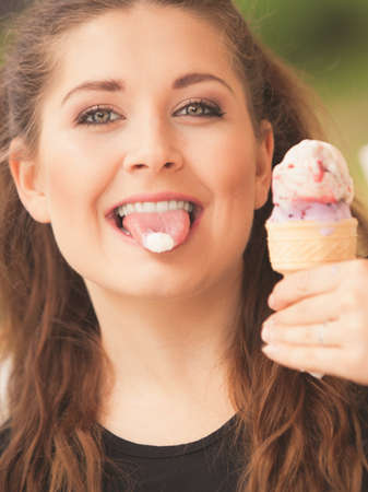 Happy funny young woman with long brown hair eating ice cream having fun.