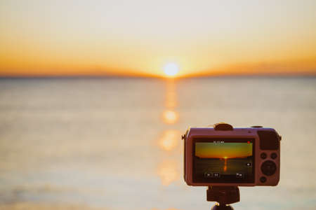 Professional camera taking picture film video of sunrise over sea surface, Greece