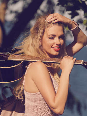 Hippie looking young adult woman wearing gypsy outfit having acoustic guitar. Female playing music in park.の写真素材