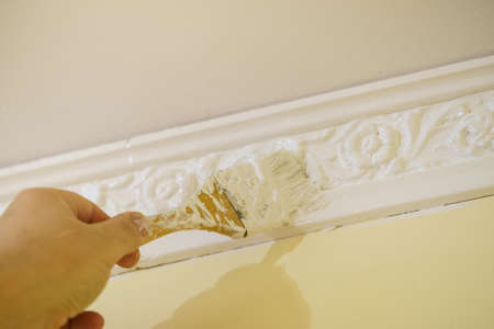 Person painting white wall decoration using brush tool. House renovation details concept.の写真素材