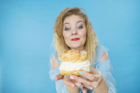 Sweets, junk food, sugar temptation on diet concept. Woman holding sweet delicious cream cupcakeの写真素材