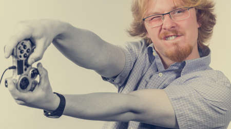 Nerd geek young adult man playing on the video console holding game pad. Gaming gamers concept.