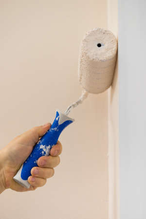 Person appplying paint on wall using roller brush. Home renovation concept.の写真素材