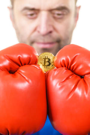 Man wearing red boxing gloves holding bitcoin symbol. Internet cryptocurrency state concept.の写真素材