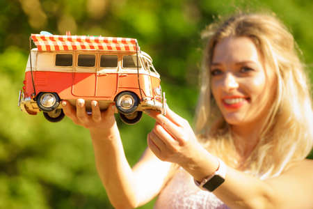 Happy woman having idea of traveling, holding hippie camper trailer decorative object model. Vehicle, summer vacations concept.の写真素材