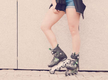 Sexy woman slim legs wearing roller skates standing outside. Sport activity concept.