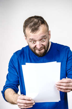 Adult surprised shocked man looking at papers, seeing something scary in documents with copy space.の写真素材